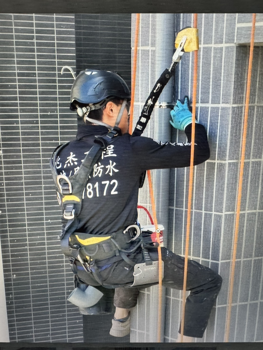 兆杰工程技師以高空繩索施作外牆配管